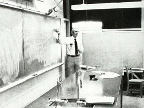 Charles Cooke in front of a chalkboard in the lab in 1984