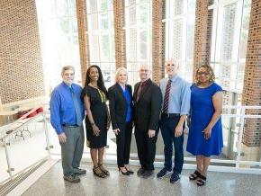 Six members of the grant writing team for the Noyce scholarship program st和 in the George Hall lobby