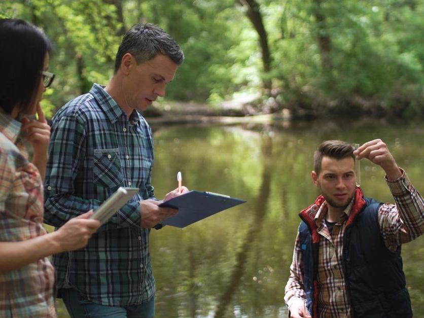 Three people testing water quality of river